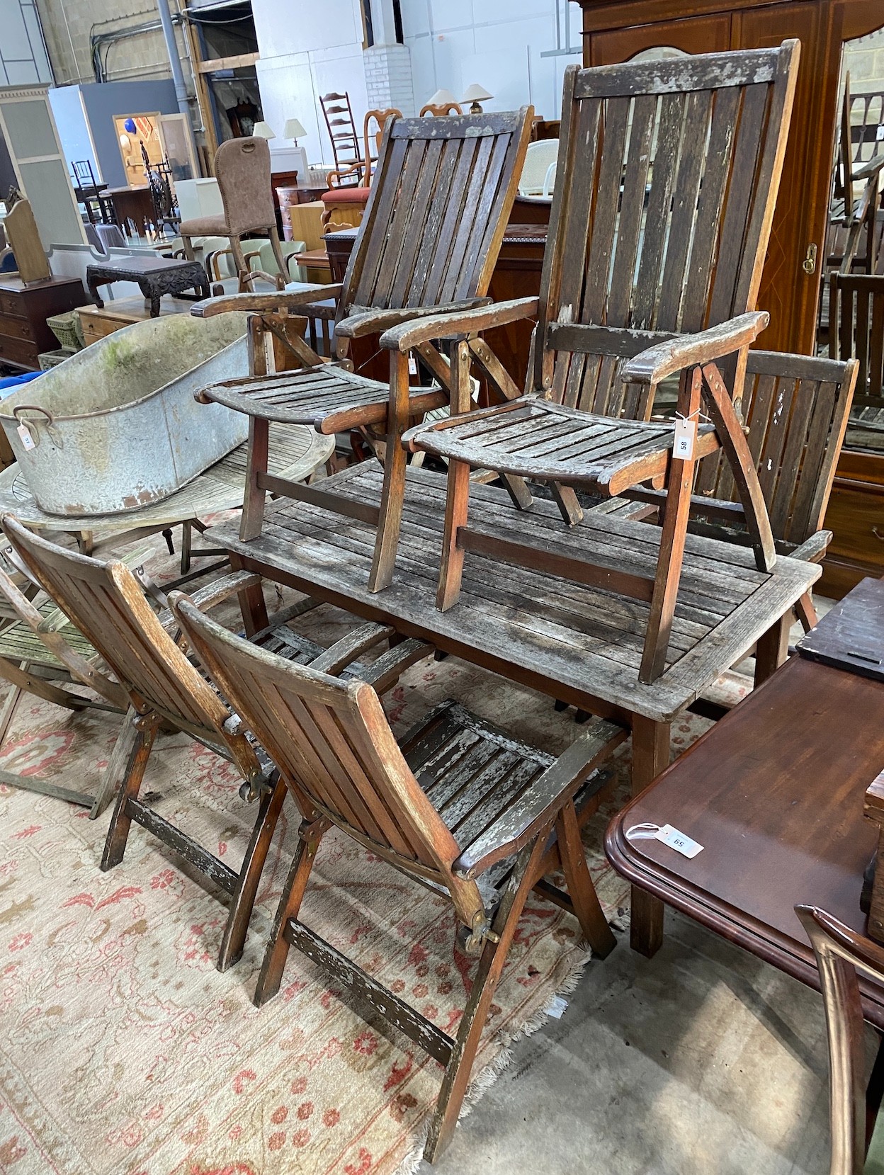 A rectangular weathered teak garden table, length 151cm, depth 70cm, height 73cm and six folding elbow chairs